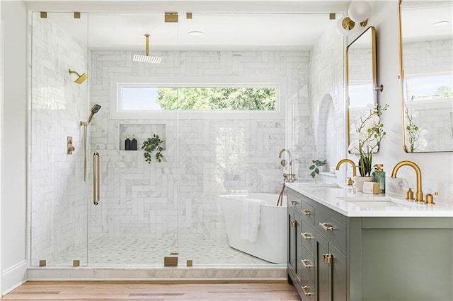 full bath with a freestanding tub, wood finished floors, a sink, double vanity, and a stall shower