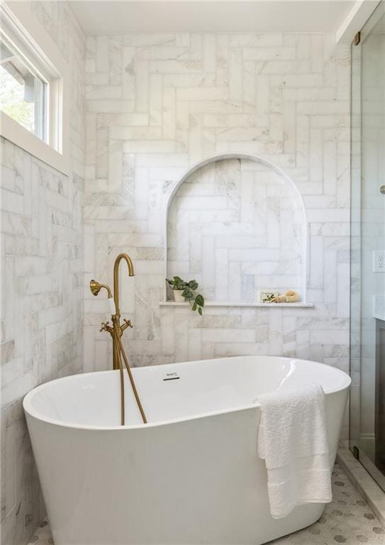 bathroom featuring a freestanding tub and tile walls