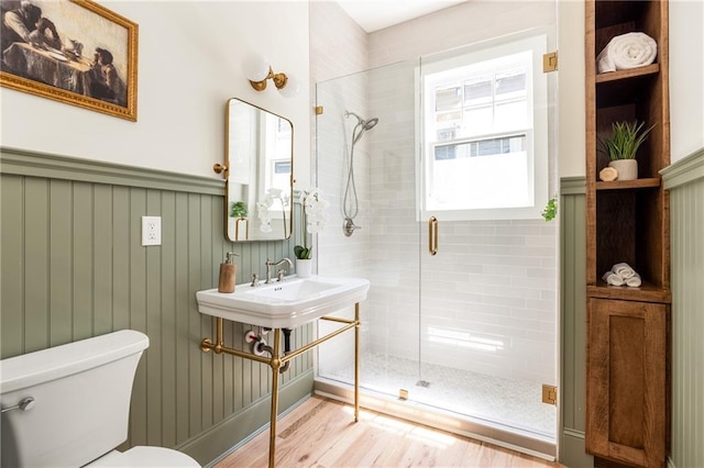 full bath with toilet, a shower stall, and wood finished floors