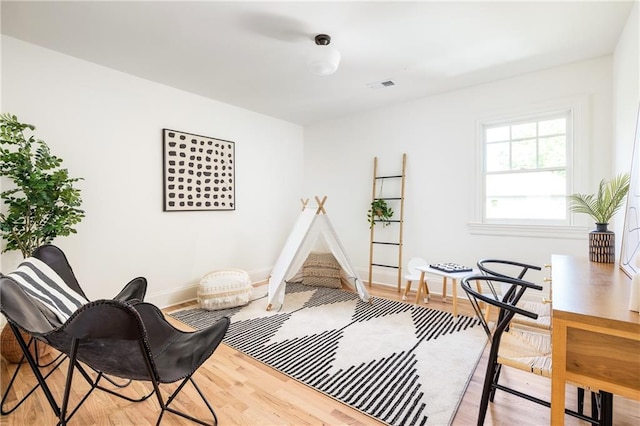 living area featuring wood finished floors, visible vents, and baseboards