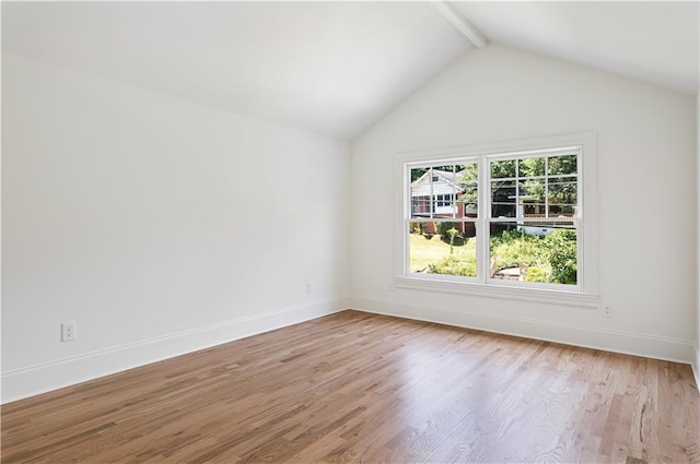 spare room with lofted ceiling with beams, light wood-style floors, and baseboards