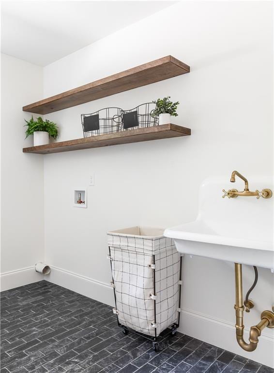 clothes washing area featuring laundry area, hookup for a washing machine, baseboards, and a sink