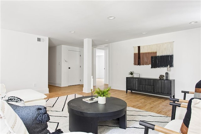 living area featuring baseboards, light wood finished floors, visible vents, and recessed lighting