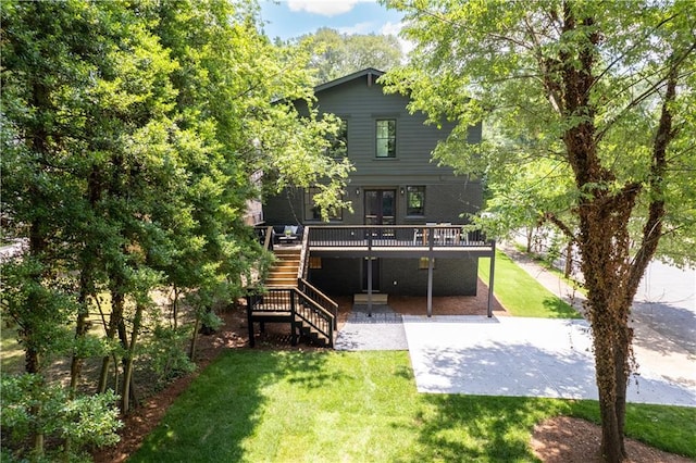 rear view of property featuring a yard, a deck, and stairs