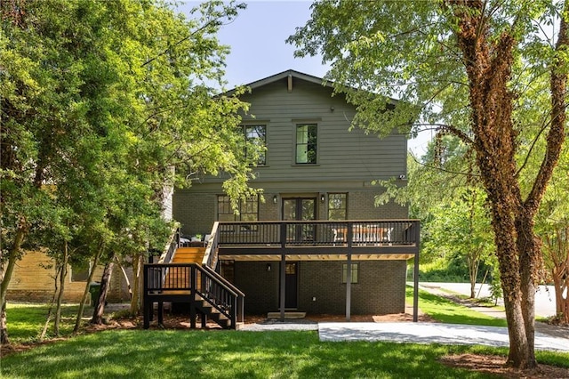 rear view of house with a yard, stairway, a deck, and brick siding