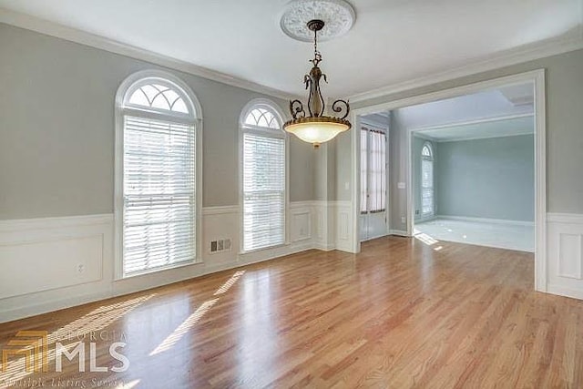 222 Chadmore Ln, Tyrone, GA 30290 - unfurnished dining area with ornamental molding, a decorative wall, wainscoting, and light wood-style flooring