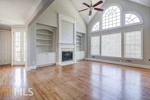 222 Chadmore Ln, Tyrone, GA 30290 - unfurnished living room with ceiling fan, built in shelves, a fireplace, wood finished floors, and high vaulted ceiling