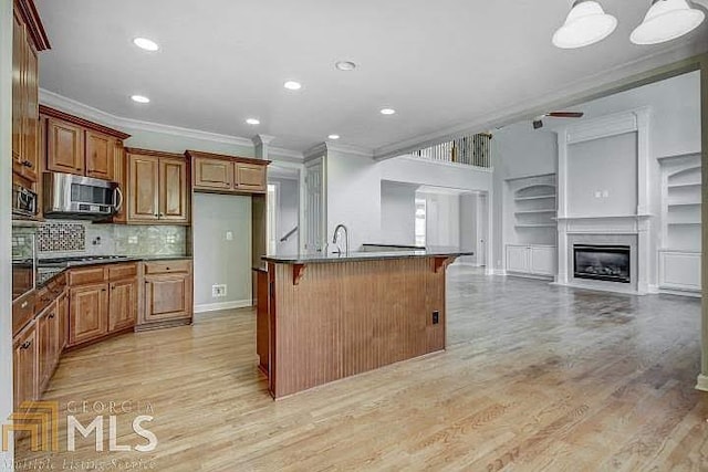 222 Chadmore Ln, Tyrone, GA 30290 - kitchen featuring stainless steel microwave, ornamental molding, open floor plan, a kitchen bar, and light wood-style flooring