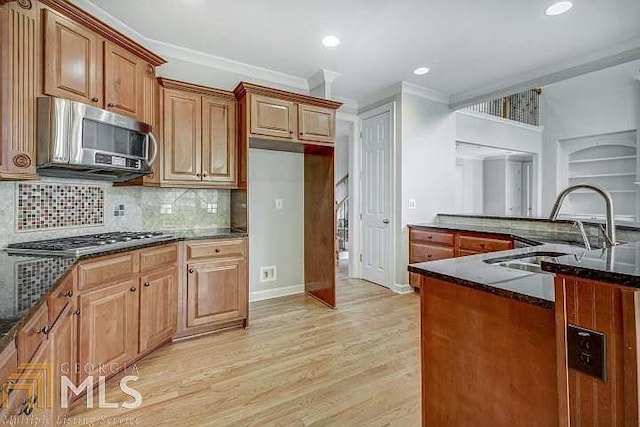 222 Chadmore Ln, Tyrone, GA 30290 - kitchen featuring appliances with stainless steel finishes, light wood-style flooring, decorative backsplash, crown molding, and dark stone countertops