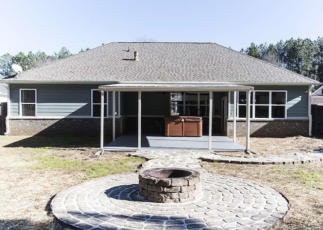 rear view of house featuring a sunroom, a hot tub, a patio area, and a fire pit