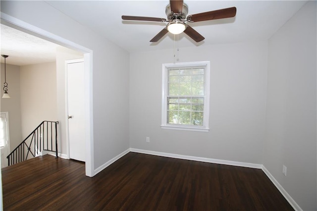 unfurnished room featuring baseboards and dark wood-style flooring