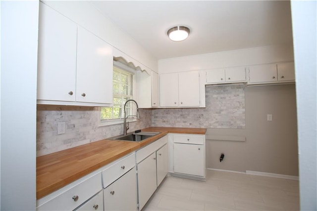 kitchen with a sink, baseboards, tasteful backsplash, and white cabinets