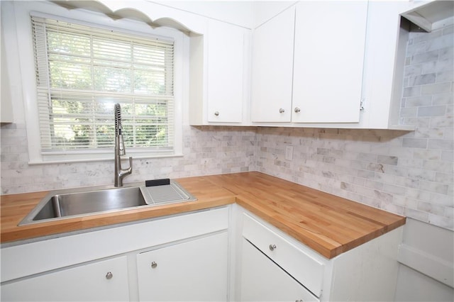 kitchen featuring a sink, white cabinetry, backsplash, and butcher block countertops