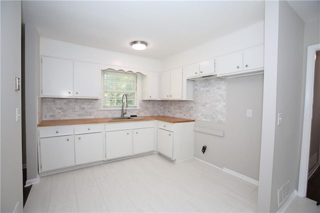 kitchen featuring a sink, visible vents, backsplash, and white cabinets