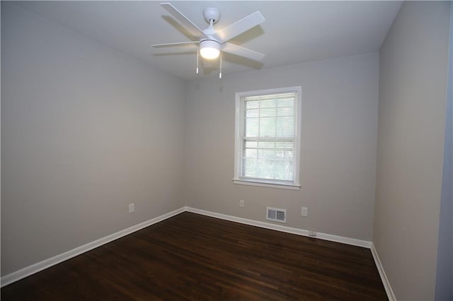 spare room with visible vents, a ceiling fan, baseboards, and dark wood-style flooring