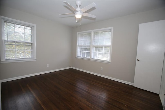 spare room featuring plenty of natural light, dark wood-type flooring, and baseboards