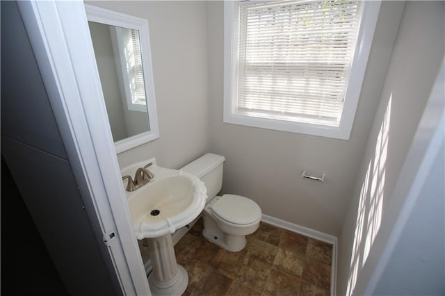 bathroom featuring toilet, baseboards, and a sink