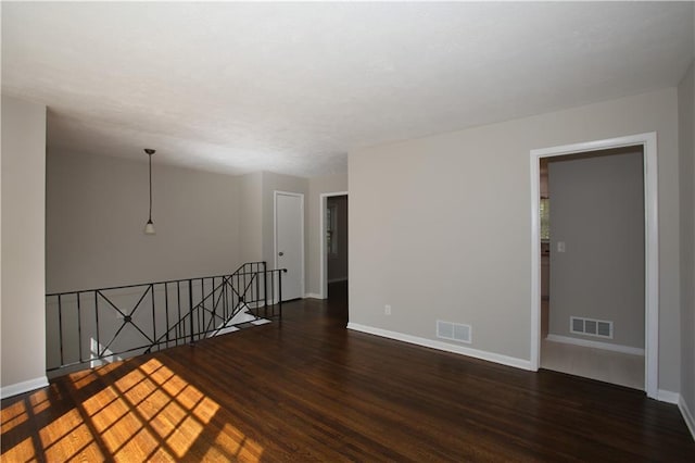 spare room with visible vents, baseboards, and wood finished floors