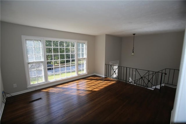 spare room with visible vents, baseboards, and dark wood finished floors