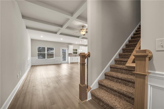 staircase with coffered ceiling, ceiling fan, hardwood / wood-style flooring, and beamed ceiling