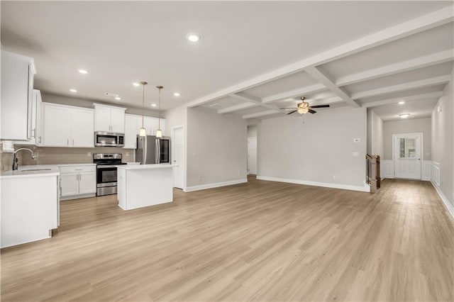 kitchen with a kitchen island, appliances with stainless steel finishes, pendant lighting, beamed ceiling, and white cabinets