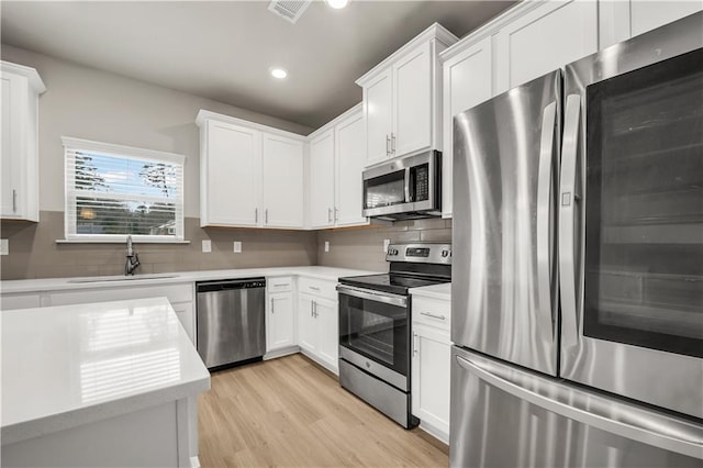 kitchen featuring backsplash, appliances with stainless steel finishes, sink, and white cabinets