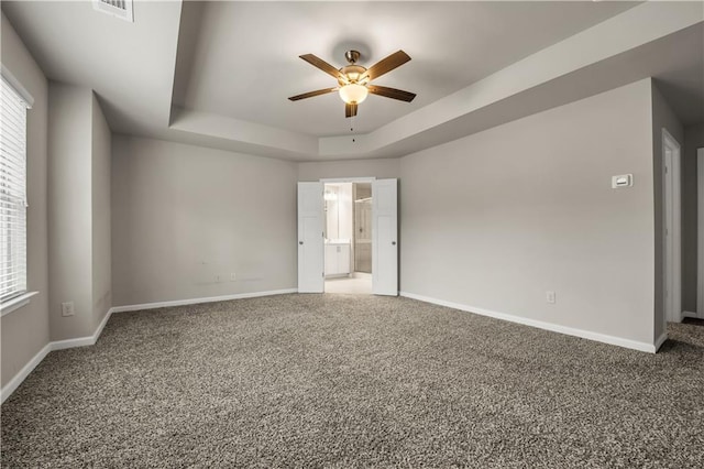 carpeted spare room with ceiling fan and a tray ceiling