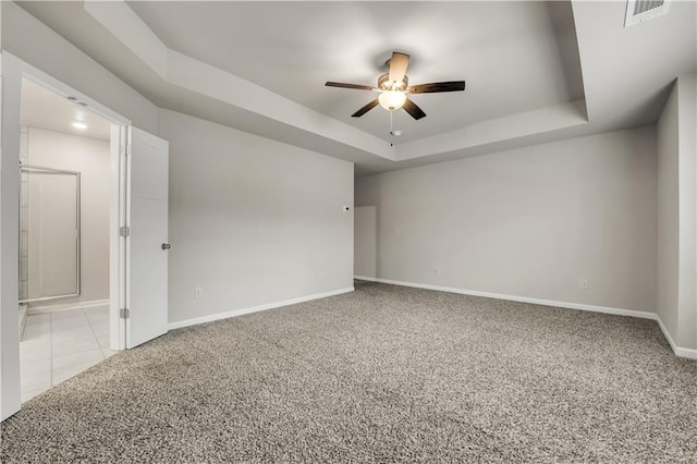 carpeted spare room featuring ceiling fan and a raised ceiling