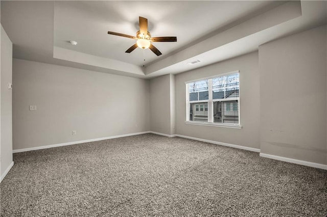 carpeted spare room with ceiling fan and a raised ceiling