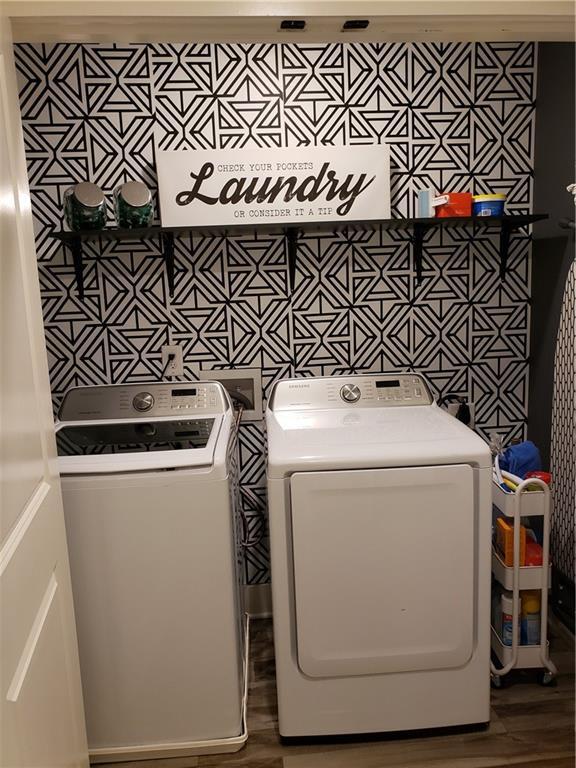 laundry area featuring wood-type flooring, washer hookup, and washer and clothes dryer