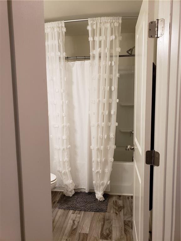 bathroom with shower / bath combination with curtain, hardwood / wood-style flooring, and toilet