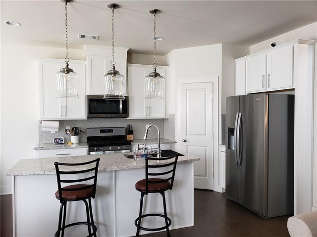 kitchen featuring white cabinetry, an island with sink, pendant lighting, sink, and appliances with stainless steel finishes