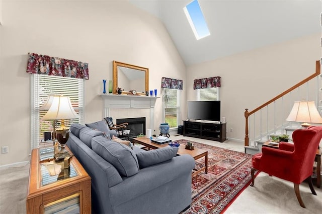 living room with a tiled fireplace, a skylight, carpet, and plenty of natural light