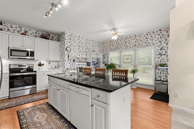 kitchen with stainless steel appliances, a kitchen island, white cabinets, and sink