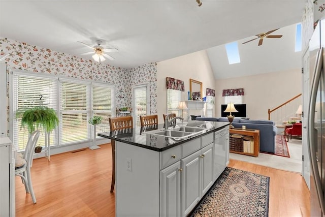 kitchen featuring sink, a center island, light hardwood / wood-style floors, white dishwasher, and a breakfast bar