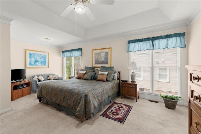 bedroom featuring ceiling fan, a tray ceiling, crown molding, and light colored carpet