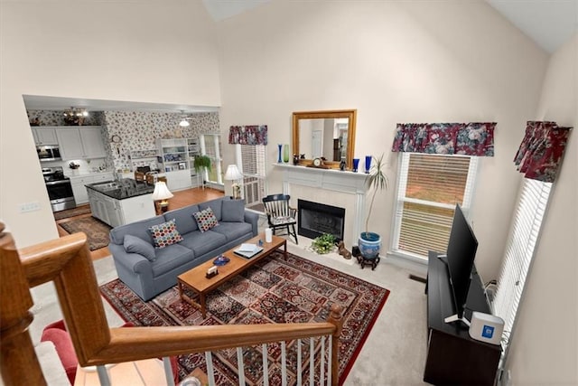 carpeted living room featuring high vaulted ceiling and a fireplace