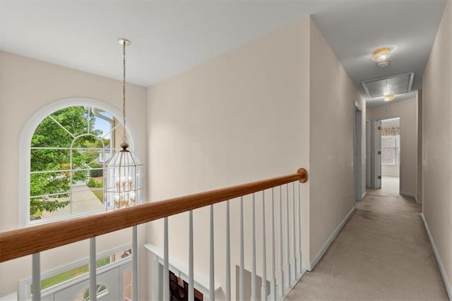 corridor featuring an inviting chandelier and light carpet