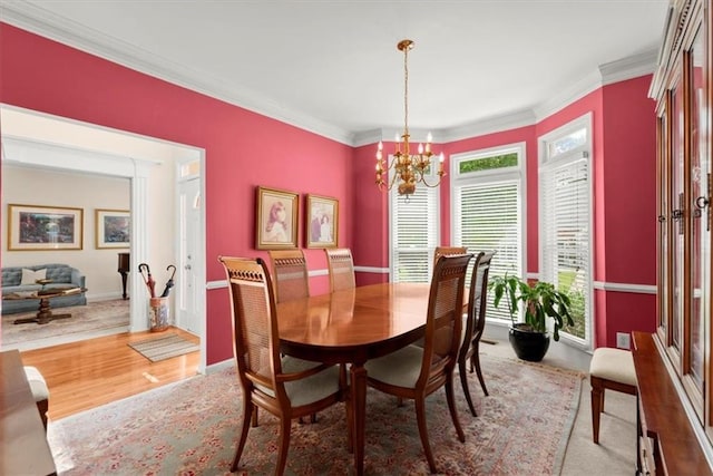 dining room with an inviting chandelier, light wood-type flooring, and crown molding