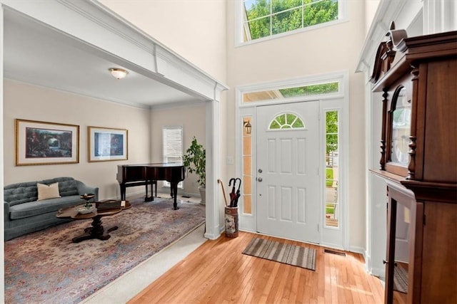 entryway with light hardwood / wood-style floors and ornamental molding