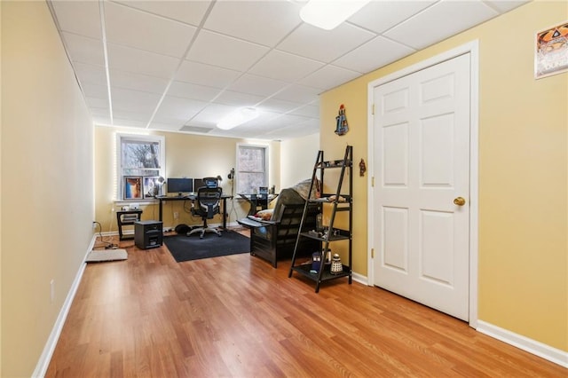 exercise area featuring wood finished floors, baseboards, and a paneled ceiling