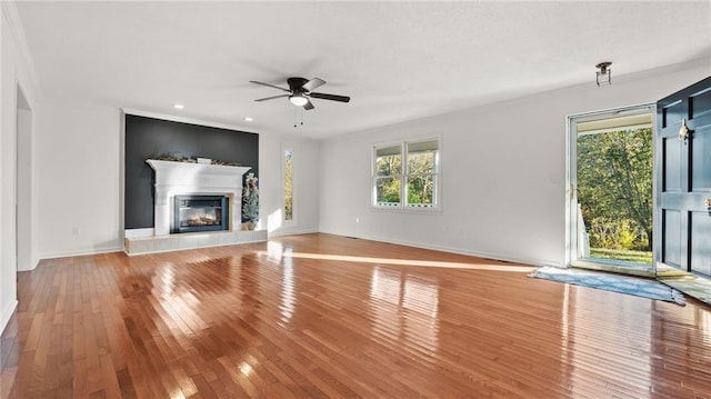 unfurnished living room featuring baseboards, a ceiling fan, a glass covered fireplace, light wood-type flooring, and recessed lighting