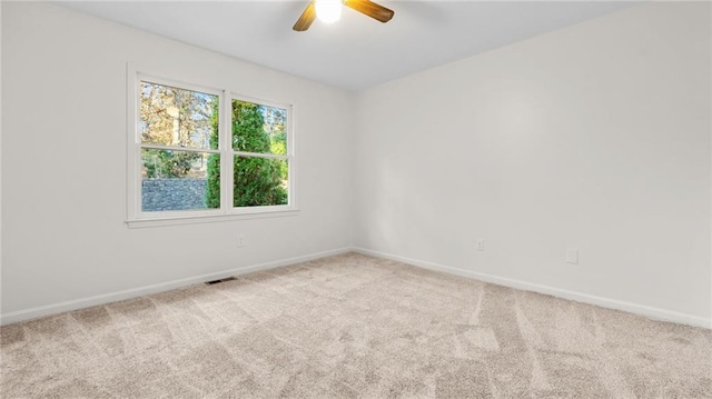 carpeted empty room featuring baseboards, visible vents, and a ceiling fan