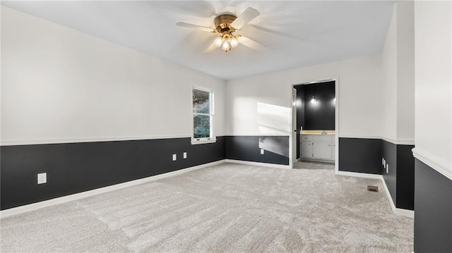 empty room with light carpet, visible vents, a ceiling fan, and baseboards