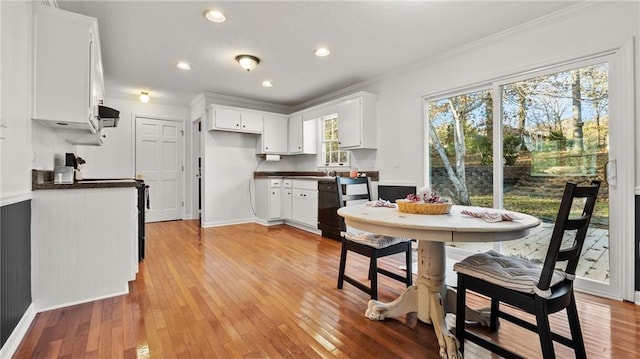 kitchen with crown molding, dark countertops, white cabinetry, and light wood-style floors