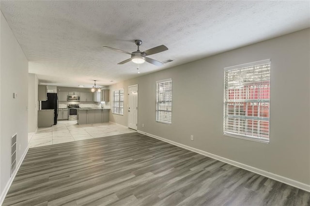 unfurnished living room with hardwood / wood-style flooring, ceiling fan, and a textured ceiling