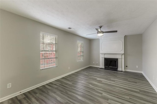 unfurnished living room featuring dark hardwood / wood-style flooring, a textured ceiling, a large fireplace, and ceiling fan