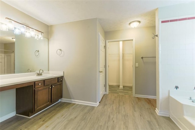 bathroom featuring vanity, hardwood / wood-style floors, plus walk in shower, and a textured ceiling