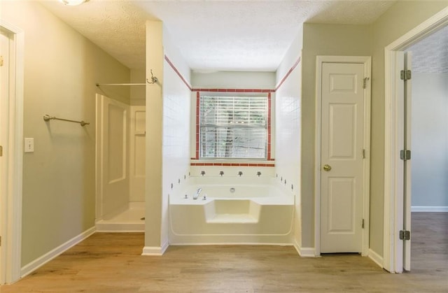 bathroom with shower with separate bathtub, wood-type flooring, and a textured ceiling