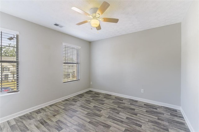 empty room with ceiling fan, dark hardwood / wood-style flooring, and a textured ceiling